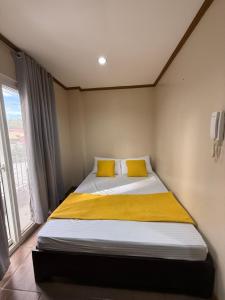 a bedroom with a bed with yellow pillows and a window at Subic Bay Baloy Long Beach Hotel in Olongapo