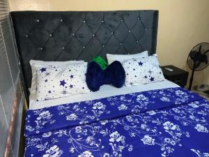 a bed with blue comforter and white pillows at Charlies 2 Bedroom Apartment Ikeja in Ikeja