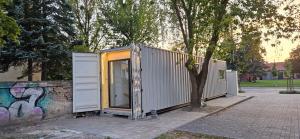 a building with an open door next to a tree at Apartament Contandair in Olsztyn