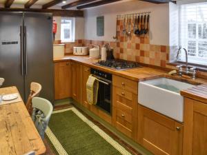 a kitchen with wooden cabinets and a stainless steel refrigerator at Rose Cottage in Bethersden
