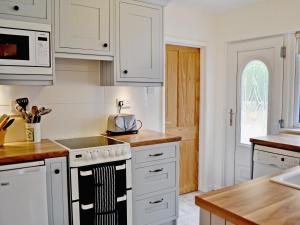 Una cocina con gabinetes blancos y un horno de estufa. en Palm Leas - E3587, en Ilfracombe