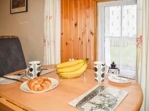 une table avec une assiette de pain et de bananes sur celle-ci dans l'établissement The Cottage, à Ollach