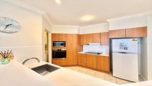 a kitchen with wooden cabinets and a white refrigerator at Breakers 2 - 7, 18 - 20 Pacific Parade in Yamba