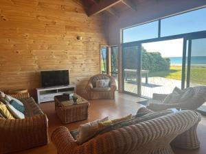 a living room with couches and a flat screen tv at Bella Vista on the Beach in Matarangi