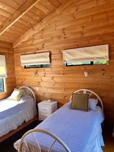 deux lits dans une chambre aux murs en bois dans l'établissement Bella Vista on the Beach, à Matarangi