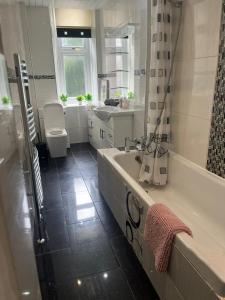 a bathroom with a tub and a toilet and a sink at 3BR Apt Near Ibrox Subway Sleeps 7 and Parking in Glasgow
