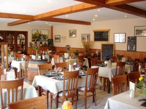 ein Restaurant mit Tischen, Stühlen und einer Tafel in der Unterkunft La Grande Fontaine in Jugon Les Lacs