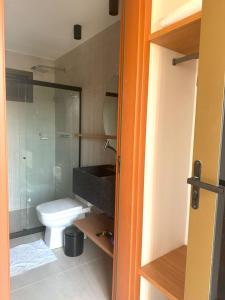 a bathroom with a toilet and a glass shower at Essence Beira mar - Porto de pedras A104 in Pôrto de Pedras