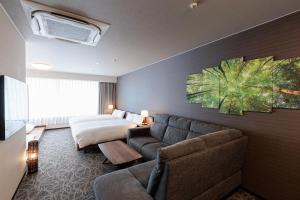 a hotel room with a couch and a bed at Hotel Silk Tree Nagoya in Nagoya