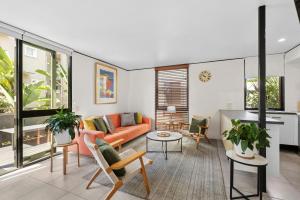 a living room with an orange couch and chairs at Hastings Villas in Noosa Heads