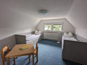 Una habitación con dos camas y una mesa y una ventana. en Aantengössel, en Born