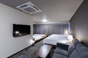 a hotel room with a bed and a couch at Hotel Silk Tree Nagoya in Nagoya