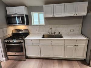 a kitchen with white cabinets and a sink and a microwave at NWW single 2nd ave Hereford Inlet Anglesea in North Wildwood