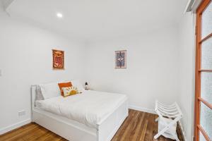 Un dormitorio blanco con una cama blanca y una ventana. en Seabreeze - Macauley's Retro Beachside Vibes, en Coffs Harbour