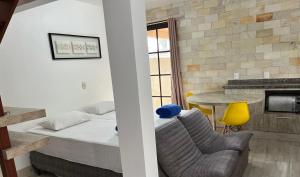 - une chambre avec un lit et une table avec une chaise jaune dans l'établissement Pousada A Cabana, à Garopaba