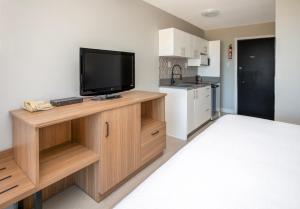 a room with a flat screen tv on a wooden entertainment center at Sea Edge Beachside Hotel in Parksville
