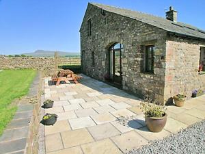 un bâtiment en pierre avec une table de pique-nique et une terrasse dans l'établissement Gallaber Cottage, à Burton in Lonsdale