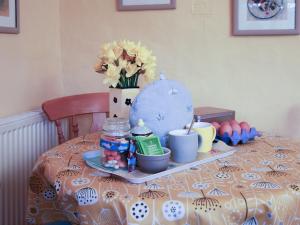 un tavolo con un piatto con uova e fiori sopra di Bell Corner Cottage a Cratfield