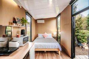 a small bedroom with a bed and a window at Kiwi Farm Cabin 2 by Tiny Away in Waitoki