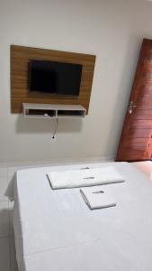 a bedroom with a bed with a tv on the wall at Pousada Tangará 