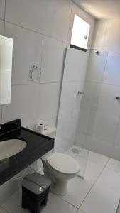 a white bathroom with a toilet and a sink at Pousada Tangará 