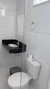 a white bathroom with a toilet and a sink at Pousada Tangará 