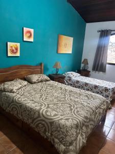a bedroom with two beds and a blue wall at Apartamento no centro de Paraty in Paraty