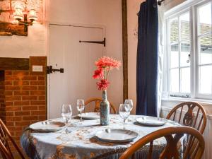 a table with chairs and a vase with flowers on it at The Cottage At Harple Farm in Detling