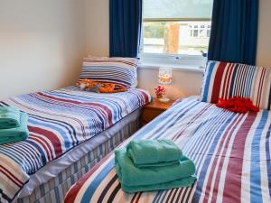 a room with two beds with towels and a window at Fairways in Beadnell +3 photos