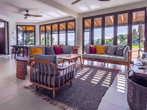 a living room with couches and tables and windows at Villa Hermanos Luxury Home with Ocean View in Sámara
