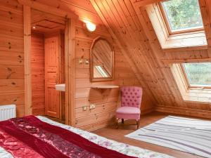 a bedroom in a log cabin with a pink chair at Foxglove- Uk48308 in Staintondale