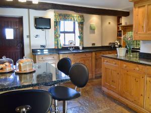 a large kitchen with wooden cabinets and black chairs at The Landings Cottage in Nun Monkton