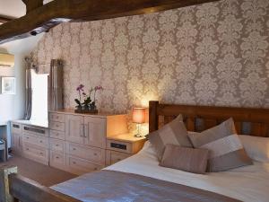 a bedroom with a bed with a dresser and a wall at The Landings Cottage in Nun Monkton