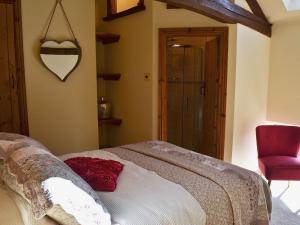 a bedroom with a bed and a red chair at The Landings Cottage in Nun Monkton +8 photos