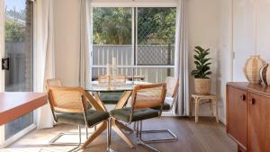 a dining room with a table and chairs and a window at Clippers 1 - Pet Friendly in Yamba +12 photos