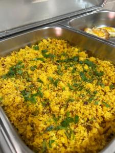 a pan filled with yellow rice with green onions at Pousada Oliveira in Remanso