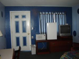 a room with a bedroom with a tv and a door at Bali Hai Motel in Yakima