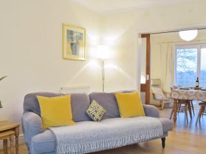 sala de estar con sofá azul y almohadas amarillas en Rosevene, en Cardigan