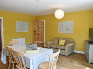 a dining room with a table and chairs and a couch at Alice Cottage in Embleton