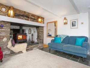 een woonkamer met een blauwe bank en een open haard bij Railway Cottage in Camelford