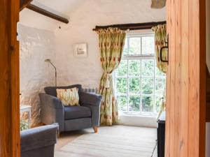 ein Wohnzimmer mit einer Couch und einem Fenster in der Unterkunft Scrumpy Cottage in Bodmin