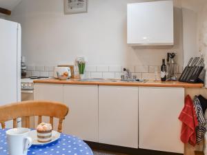 eine Küche mit weißen Schränken und einem Tisch mit Kuchen in der Unterkunft Scrumpy Cottage in Bodmin + 16 Fotos