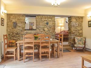 una sala da pranzo con parete in pietra, tavolo e sedie di Cowslip Cottage a Roch