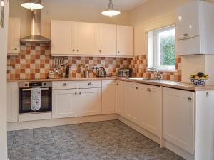 una cucina con mobili bianchi e un lavandino di Cowslip Cottage a Roch Altre 13 foto