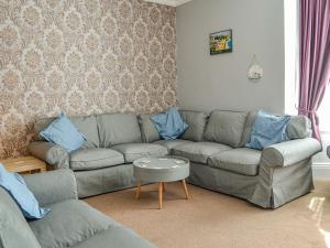 a living room with a gray couch and blue pillows at Zack's Seaside Stay in Bridlington