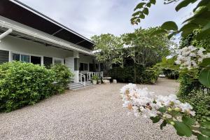 a house with a gravel driveway and flowering plants at Bann Kam B&B in Krabi town
