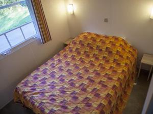 NaucelleMobil home cosy avec terrasse au camping de Naucelle - API-1-52-585的卧室里有一张床，床上铺着色彩鲜艳的被子 更多18张照片