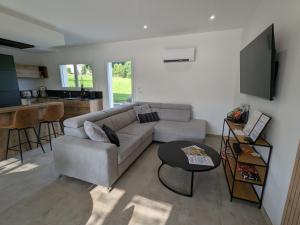 ein Wohnzimmer mit Sofa und Tisch in der Unterkunft Maison de vacances raffinée avec terrasse et piscine partagée - FR-1-589-837 in Dounoux