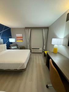 une chambre d'hôtel avec un grand lit et un bureau dans l'établissement Halsted Inn and Suites Harvey - Chicago Southland, à Harvey