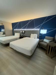 une chambre d'hôtel avec deux lits et un canapé dans l'établissement Halsted Inn and Suites Harvey - Chicago Southland, à Harvey